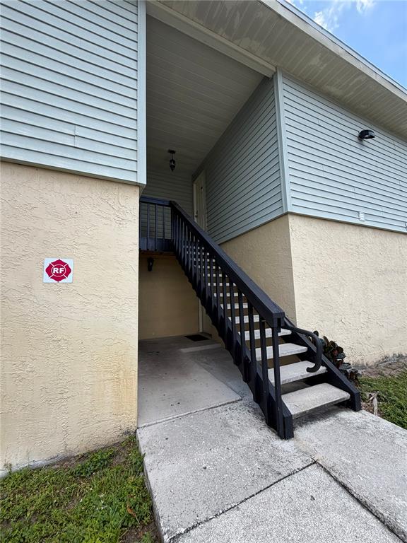 An exterior view shows a beige building with a staircase leading to an upper entrance — 237 RED MAPLE PLACE, BRANDON, FL