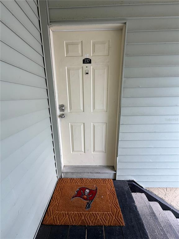 An exterior view of a white apartment door with a Tampa Bay Buccaneers doormat — 237 RED MAPLE PLACE, BRANDON, FL