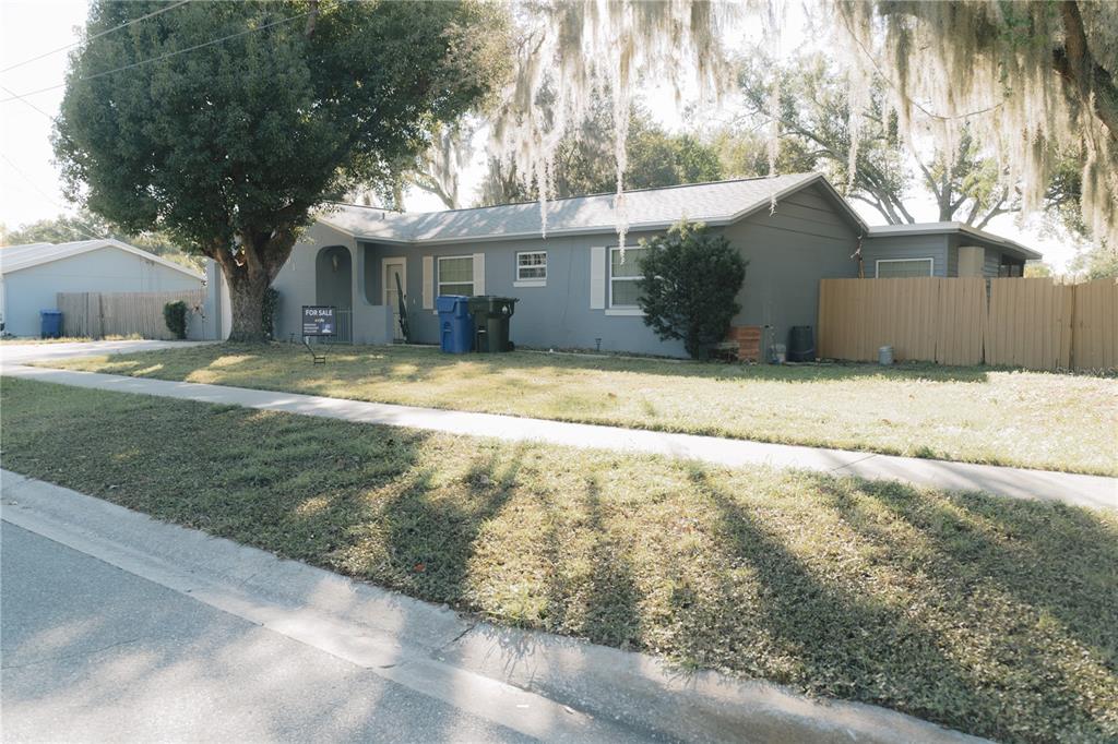 A gray single-story house with a front lawn, a large tree, and a wooden fence — 503 APRICOT DRIVE, OCOEE, FL