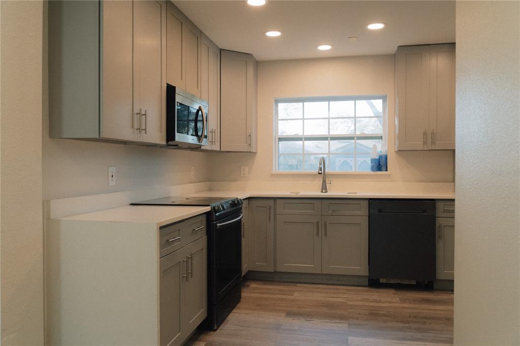 A kitchen features gray cabinets, white countertops, stainless steel appliances, and wood-look flooring — 503 APRICOT DRIVE, OCOEE, FL