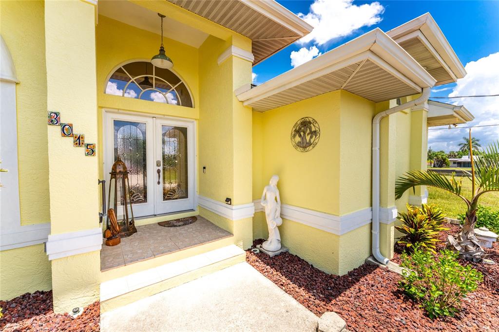 The exterior of a yellow house features a double front door and a statue — 3015 WISTERIA PLACE, PUNTA GORDA, FL