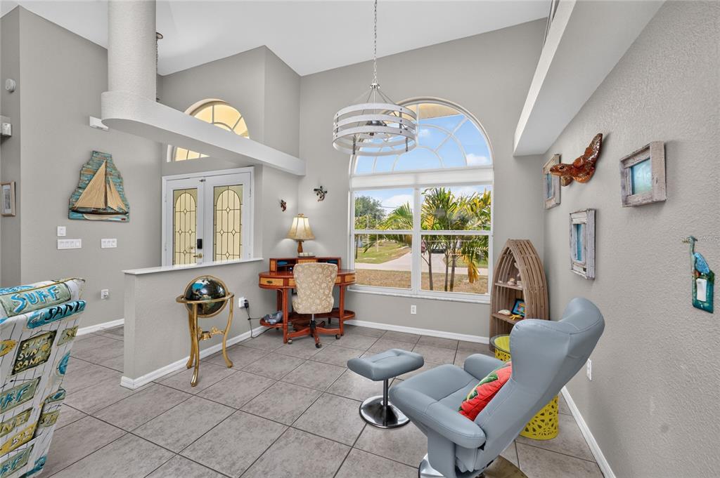 A bright room features tile flooring, a desk, a gray armchair, and a large arched window — 3015 WISTERIA PLACE, PUNTA GORDA, FL