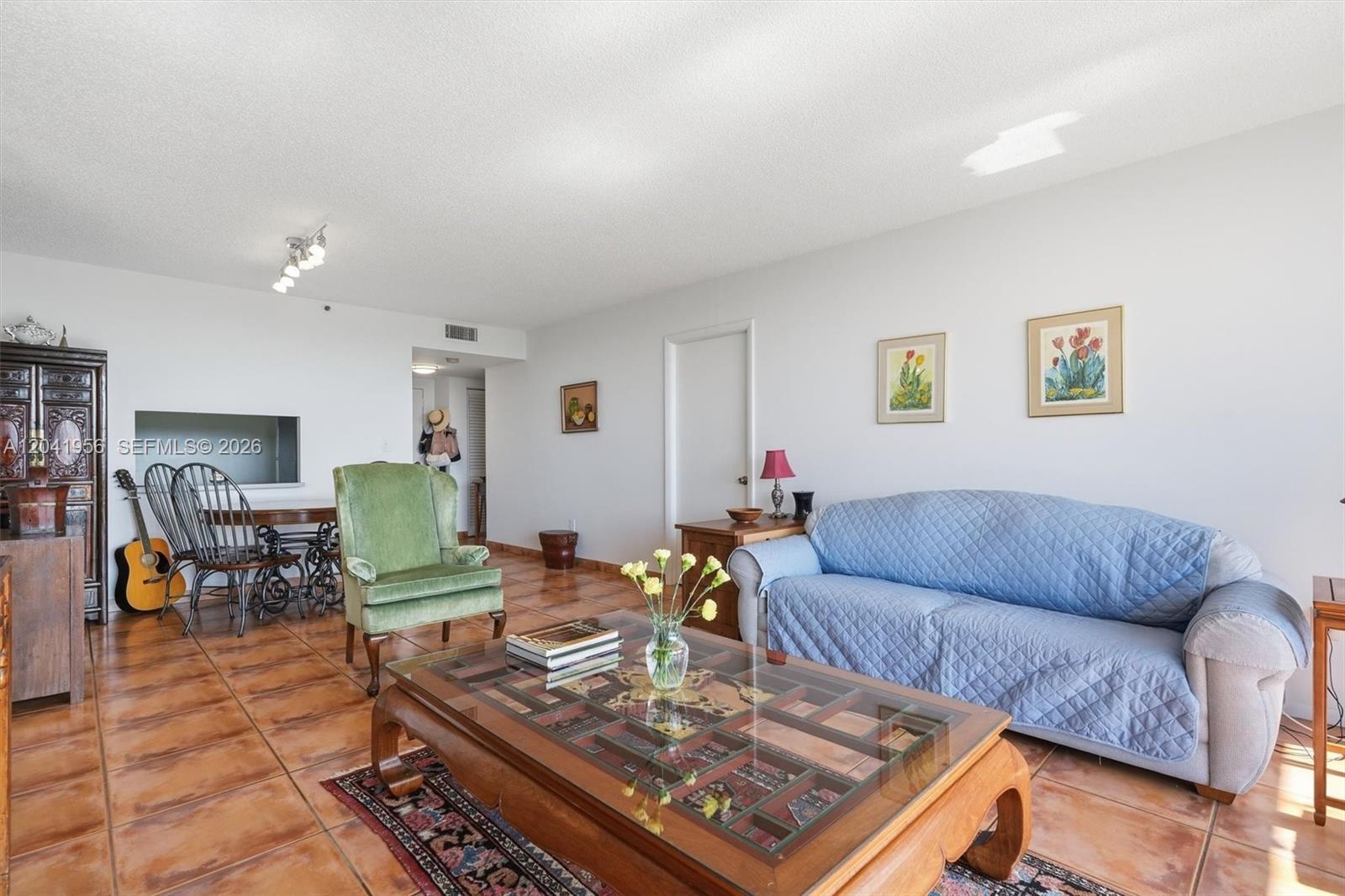 A living room features tile floors, a blue sofa, a green armchair, and a coffee table — 1470 NE 123rd St # A609, North Miami FL 33161, NORTH MIAMI, FL