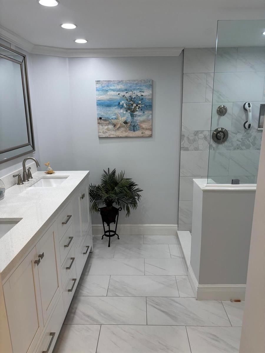 A bathroom features a double vanity, a glass-enclosed shower, and light-colored marble-look tile flooring — 60 Pelican Pointe Drive # 1020, Delray Beach FL 33483, DELRAY BEACH, FL