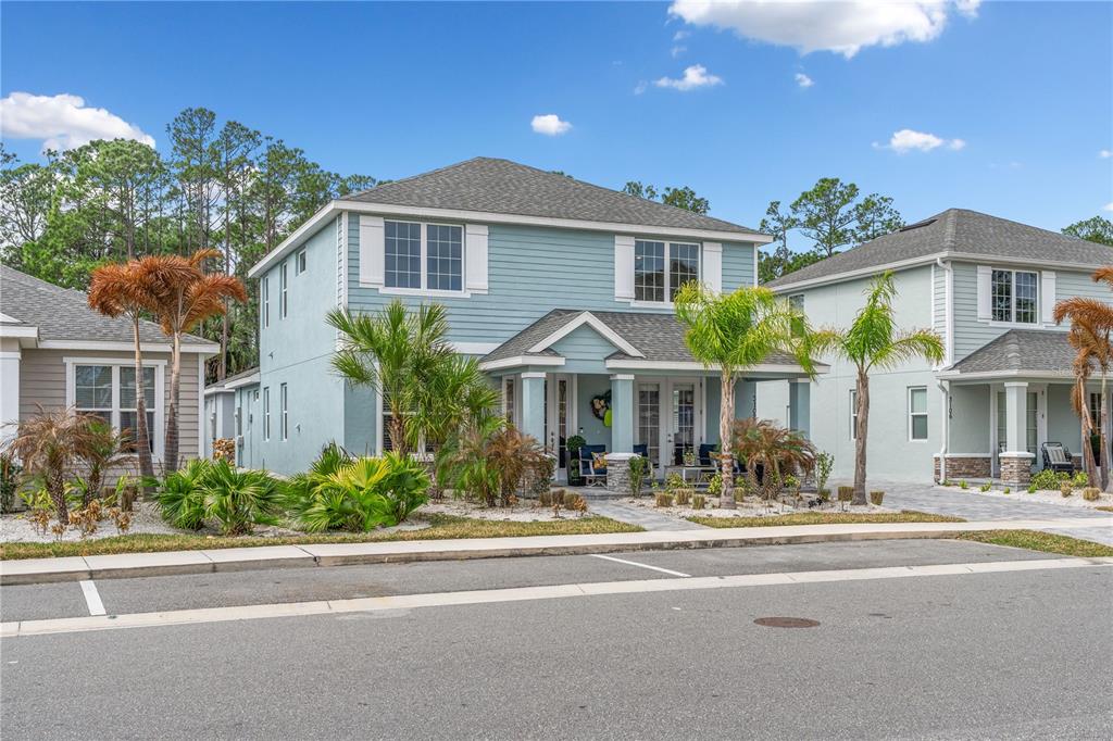 A two-story light blue house with a covered front porch and palm trees — 3102 MELETO BOULEVARD, NEW SMYRNA BEACH, FL