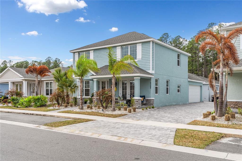 A two-story light blue house with a stone-accented porch and a paved driveway — 3102 MELETO BOULEVARD, NEW SMYRNA BEACH, FL