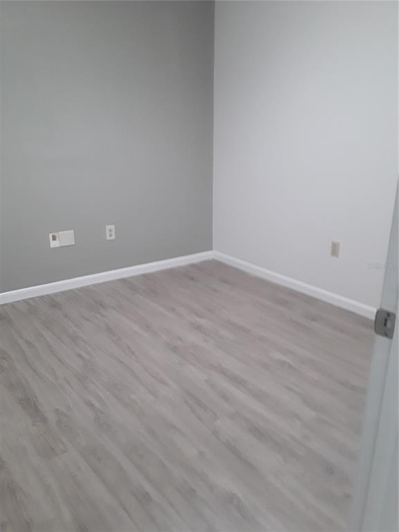 An empty room features light gray walls, white trim, and wood-look laminate flooring — 1310 N MAIN STREET, KISSIMMEE, FL