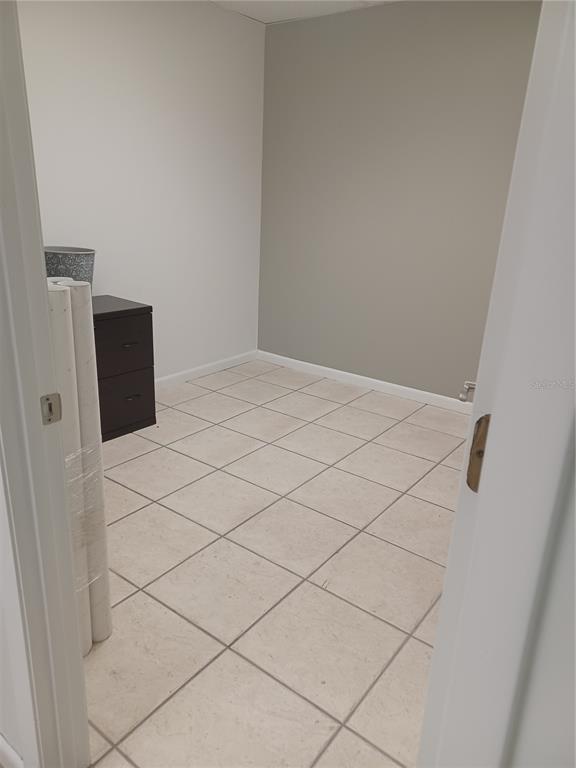 A small room with light-colored tile flooring, white walls, and a dark two-drawer filing cabinet — 1310 N MAIN STREET, KISSIMMEE, FL