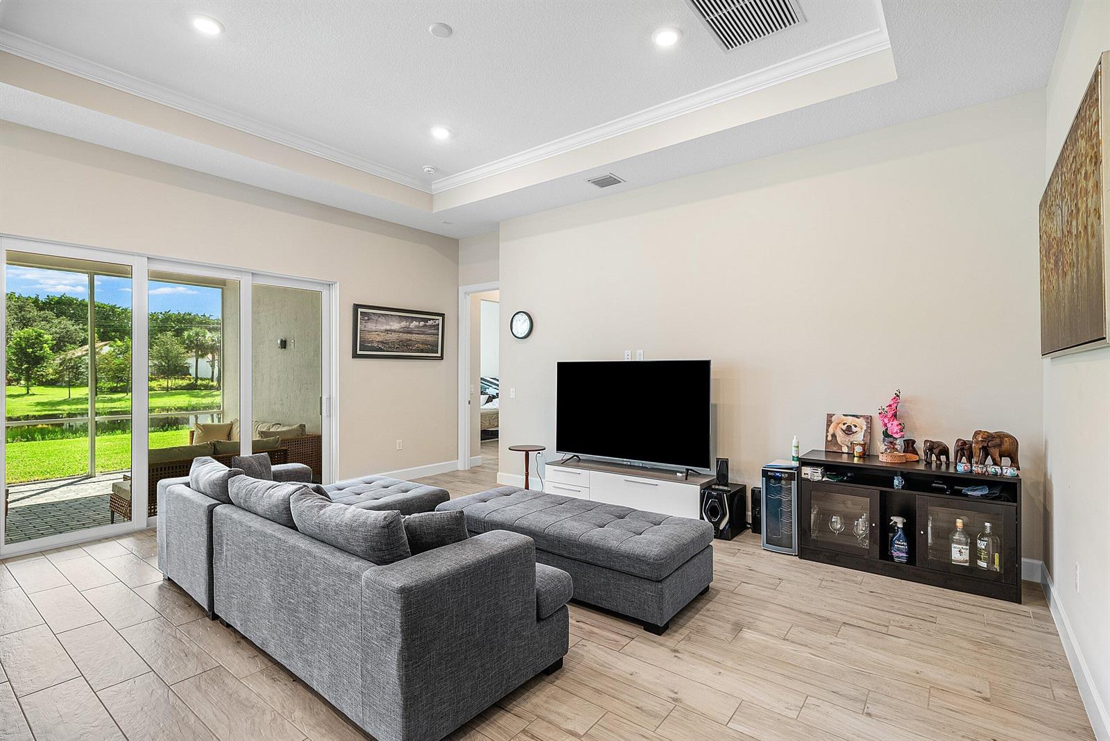 A living room features a grey sectional sofa, a television, and sliding glass doors outdoors — 349 Geillis Path, Delray Beach FL 33445, DELRAY BEACH, FL