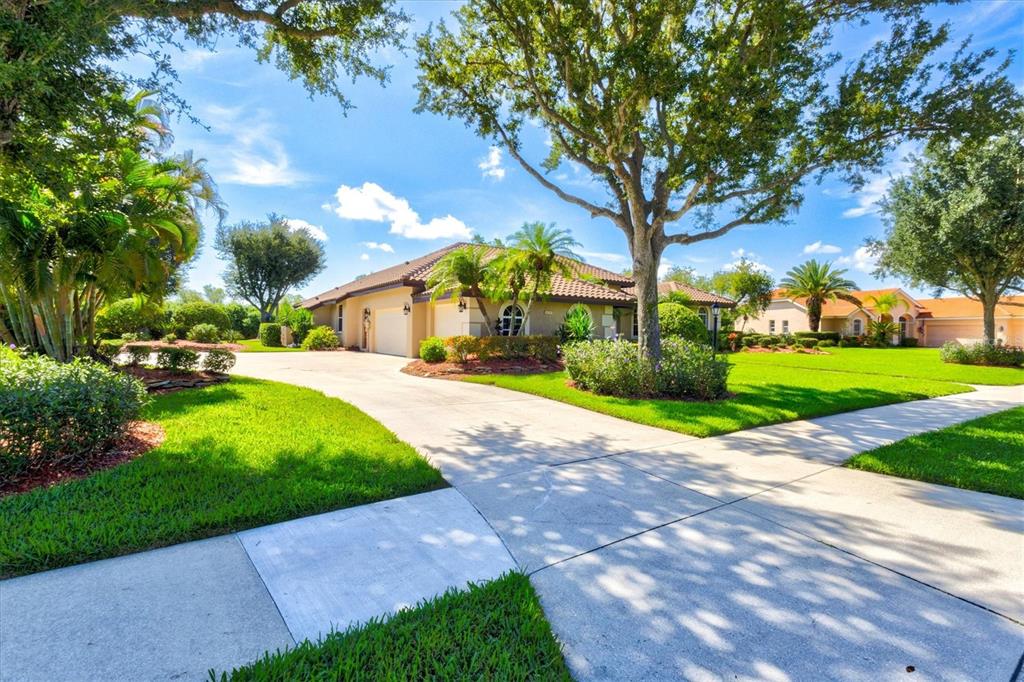An aerial view shows three houses with tile roofs situated along a lake and fields — 7373 S SERENOA DRIVE, SARASOTA, FL