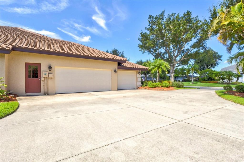 A single-story house with a concrete driveway, palm trees, and a green lawn — 7373 S SERENOA DRIVE, SARASOTA, FL