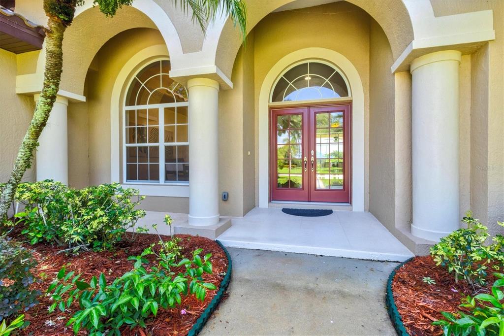 A beige house features a two-car garage, a red side door, and a concrete driveway — 7373 S SERENOA DRIVE, SARASOTA, FL