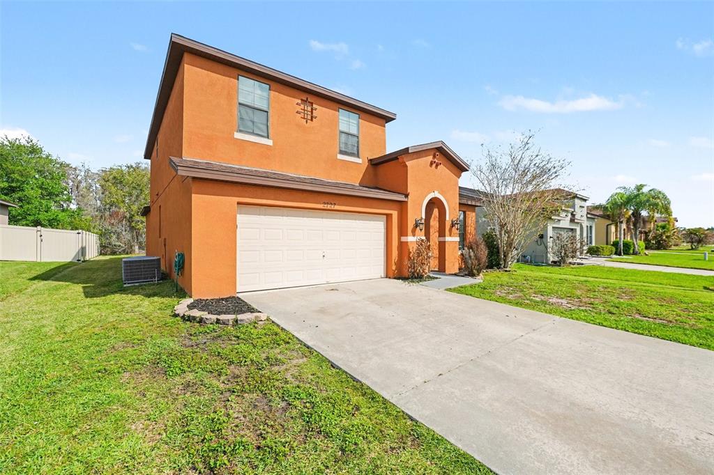 A two-story orange stucco house with a two-car garage and a concrete driveway — 2727 EAGLE CLIFF DRIVE, KISSIMMEE, FL