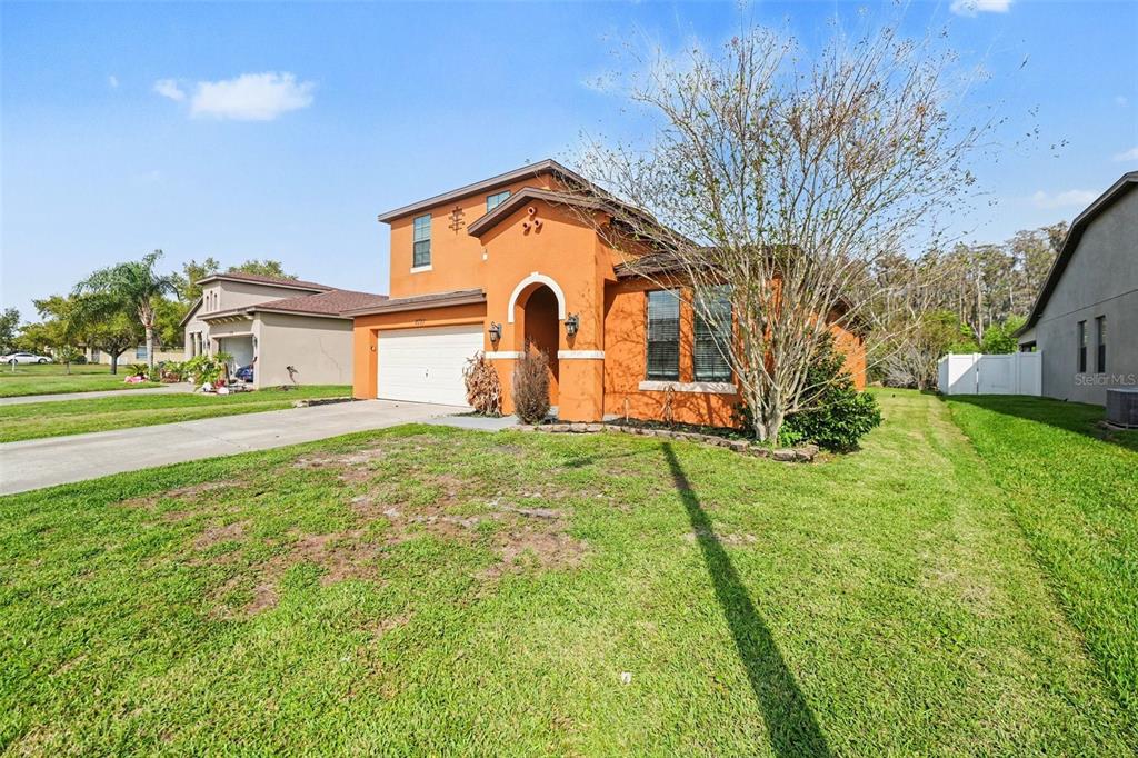 A two-story orange stucco house with a two-car garage and a front lawn — 2727 EAGLE CLIFF DRIVE, KISSIMMEE, FL