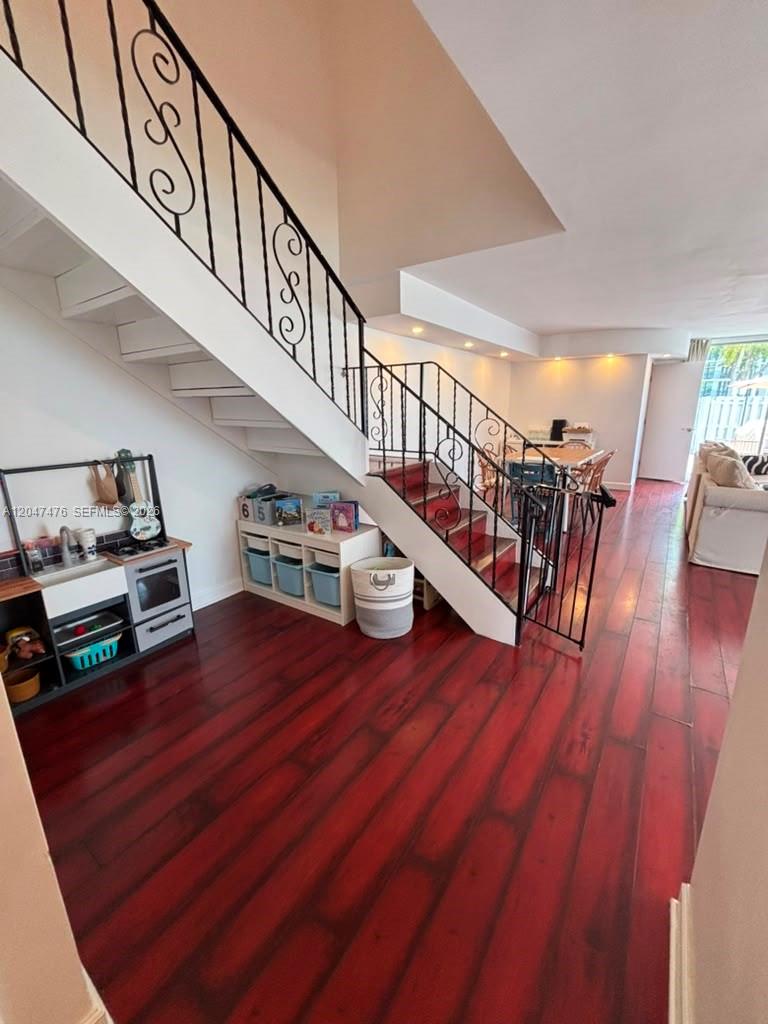 A living area features a staircase with black railings, red wood flooring, and a play kitchen — 926 NE 27th Ave # 926, Hallandale Beach FL 33009, HALLANDALE BEACH, FL