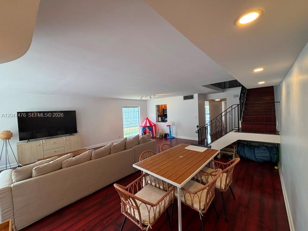 A living and dining area features dark wood flooring, a large sectional sofa, and stairs — 926 NE 27th Ave # 926, Hallandale Beach FL 33009, HALLANDALE BEACH, FL