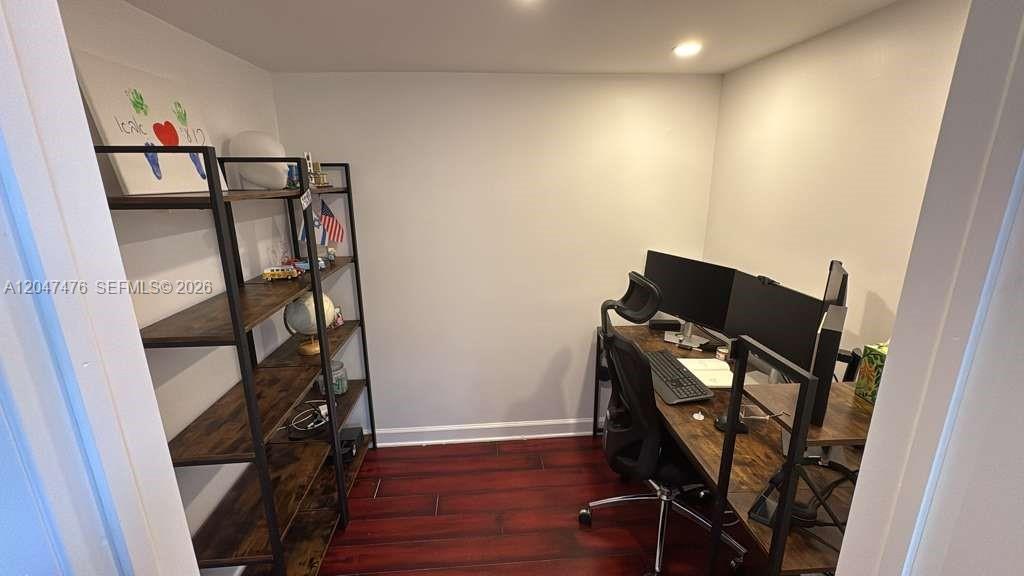 A small home office features a wooden desk, a black chair, and a tall shelving unit — 926 NE 27th Ave # 926, Hallandale Beach FL 33009, HALLANDALE BEACH, FL