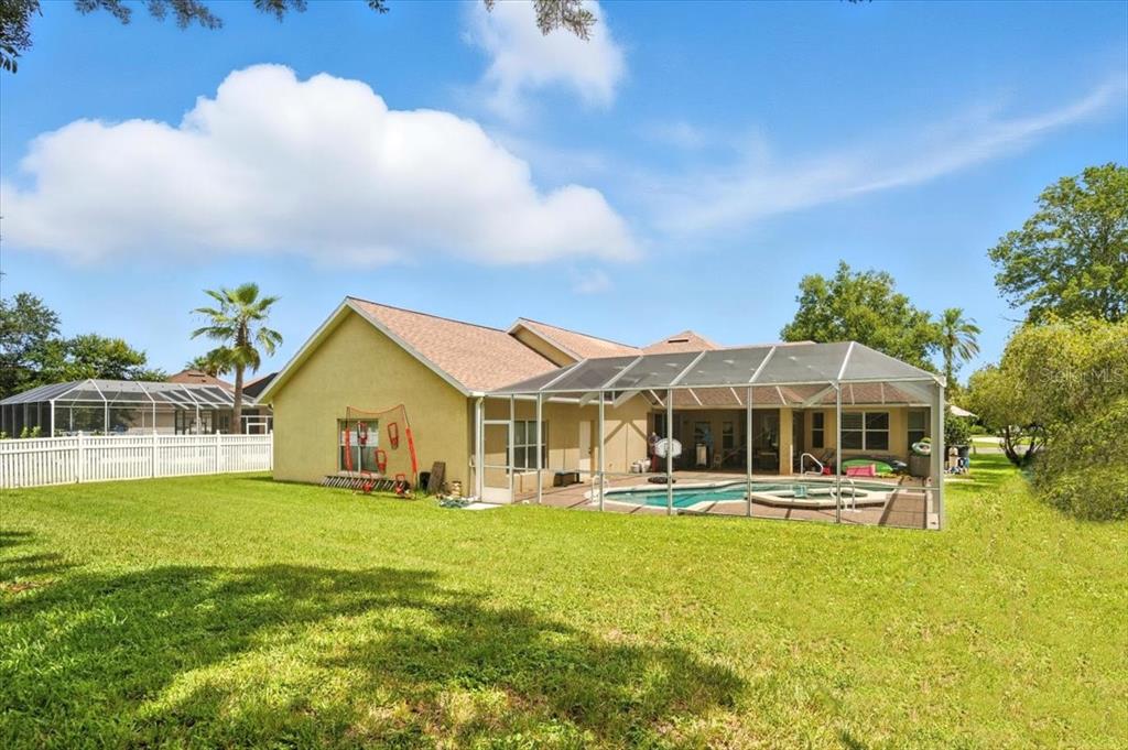 A yellow house with a screened-in pool and patio sits in a grassy backyard — 24 LAKESIDE PLACE W, PALM COAST, FL