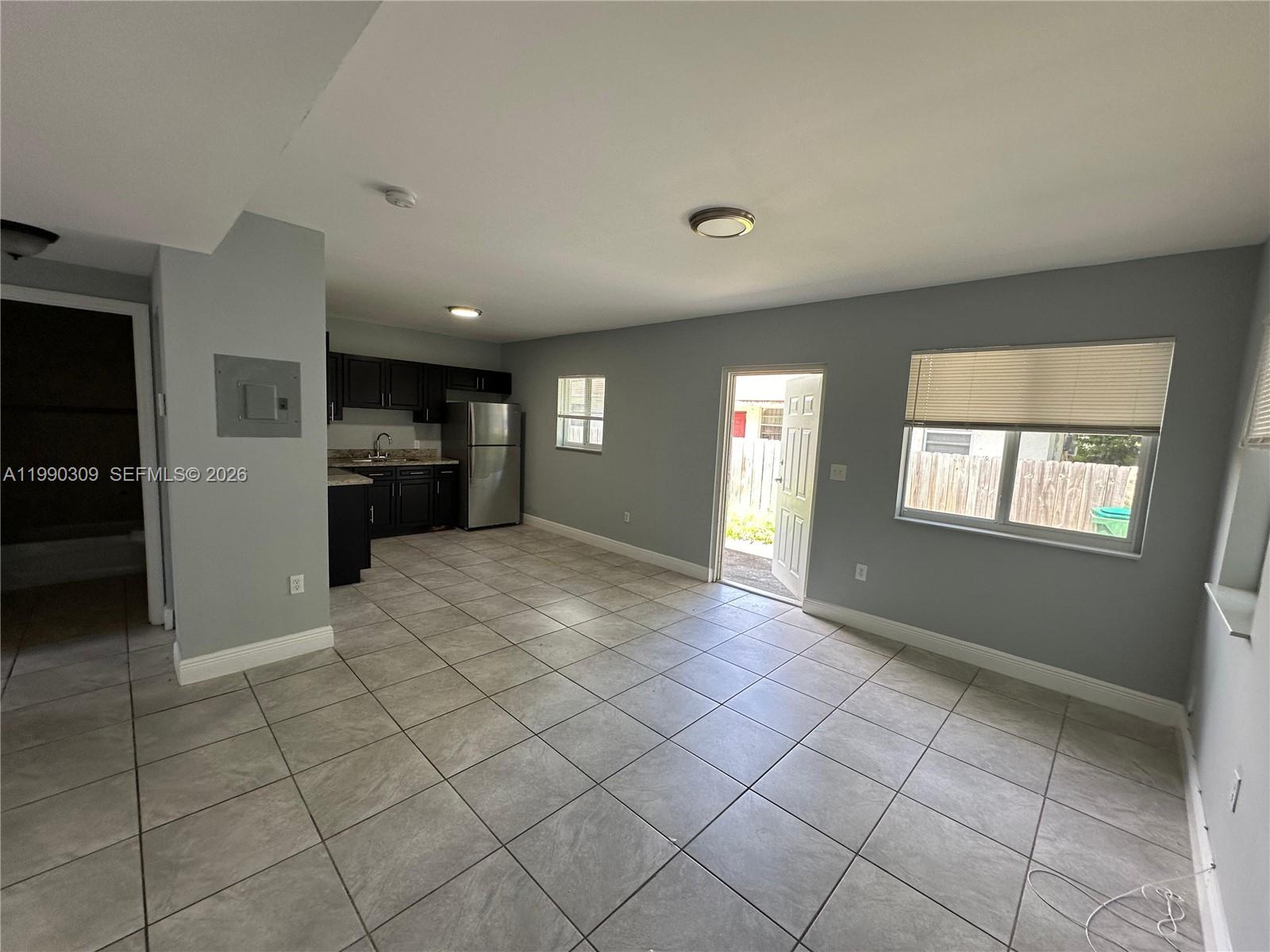 An open-concept kitchen and living area features gray walls, tile flooring, and a back door — 6801 NW 2nd Ct # 6803, Miami FL 33150, MIAMI, FL