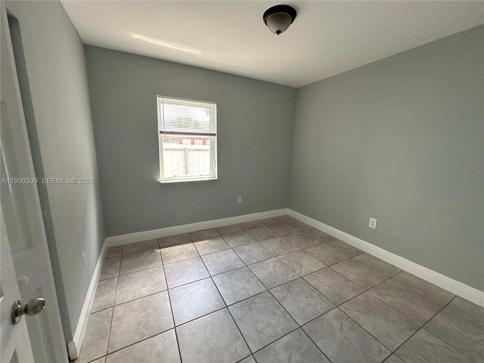 An empty room features light gray walls, white baseboards, and large square floor tiles — 6801 NW 2nd Ct # 6803, Miami FL 33150, MIAMI, FL