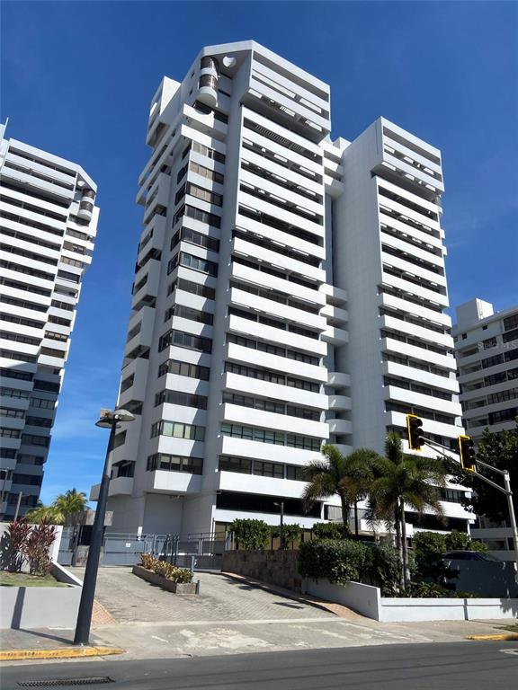 A tall, white, multi-story residential building stands under a clear blue sky — 1485 ASHFORD AVENUE UNIT 16A, SAN JUAN, PR
