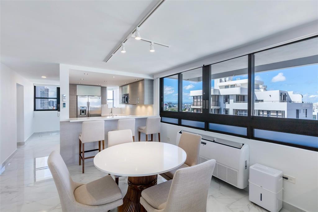 A dining area with a round table and chairs sits before a kitchen with bar seating — 1485 ASHFORD AVENUE UNIT 16A, SAN JUAN, PR