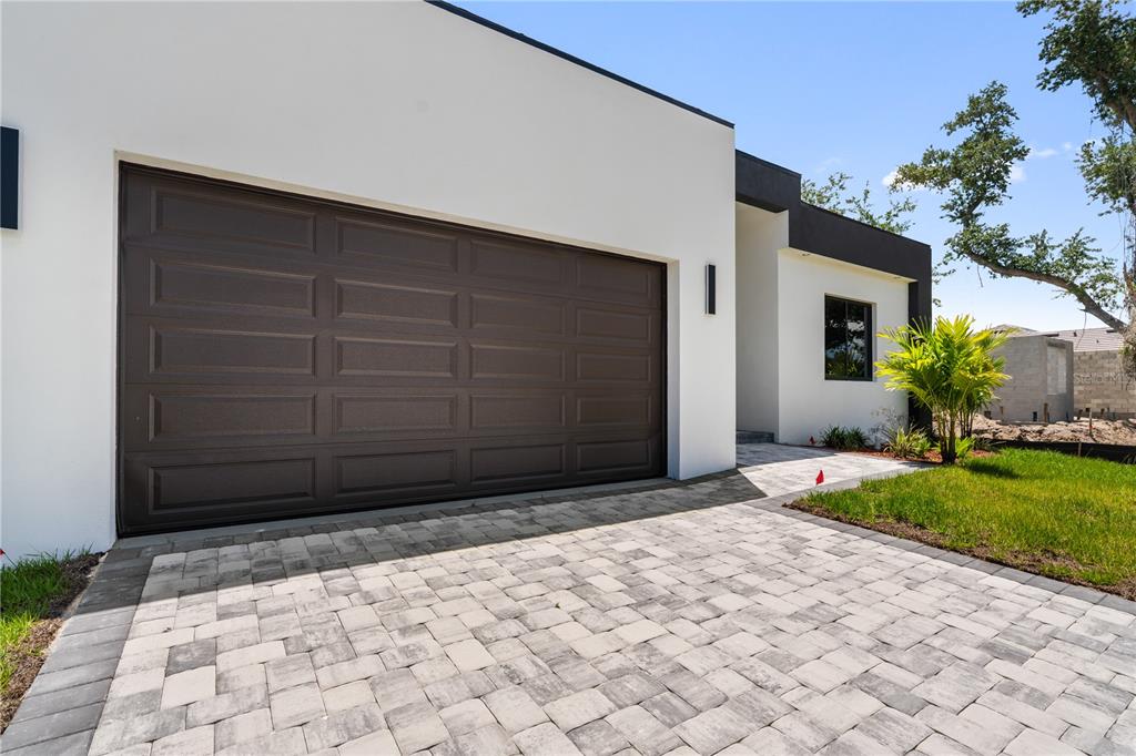 A modern house exterior features a dark brown garage door and a paved stone driveway — 10070 FLAT RIVER ST, PORT CHARLOTTE, FL