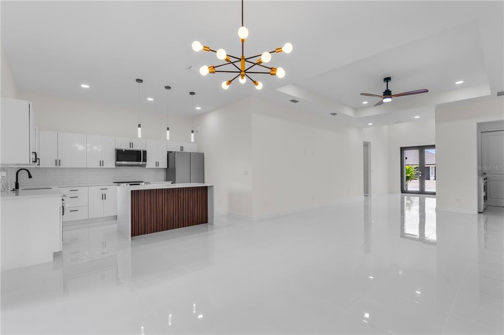 A modern kitchen with white cabinetry and a wood-paneled island opens to a spacious room — 10070 FLAT RIVER ST, PORT CHARLOTTE, FL