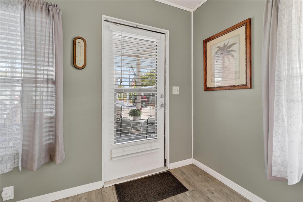 An interior view of a room with light green walls, a door, and wood-look flooring — 251 PATTERSON ROAD UNIT D32, HAINES CITY, FL