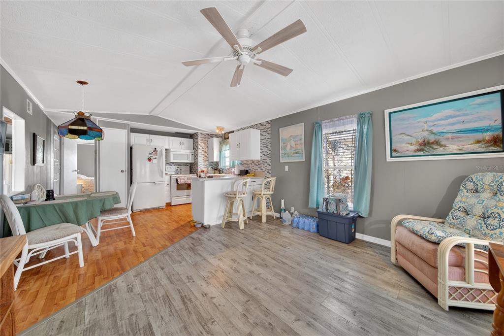 An open-concept living and dining area features wood-look flooring, a ceiling fan, and white cabinetry — 251 PATTERSON ROAD UNIT D32, HAINES CITY, FL