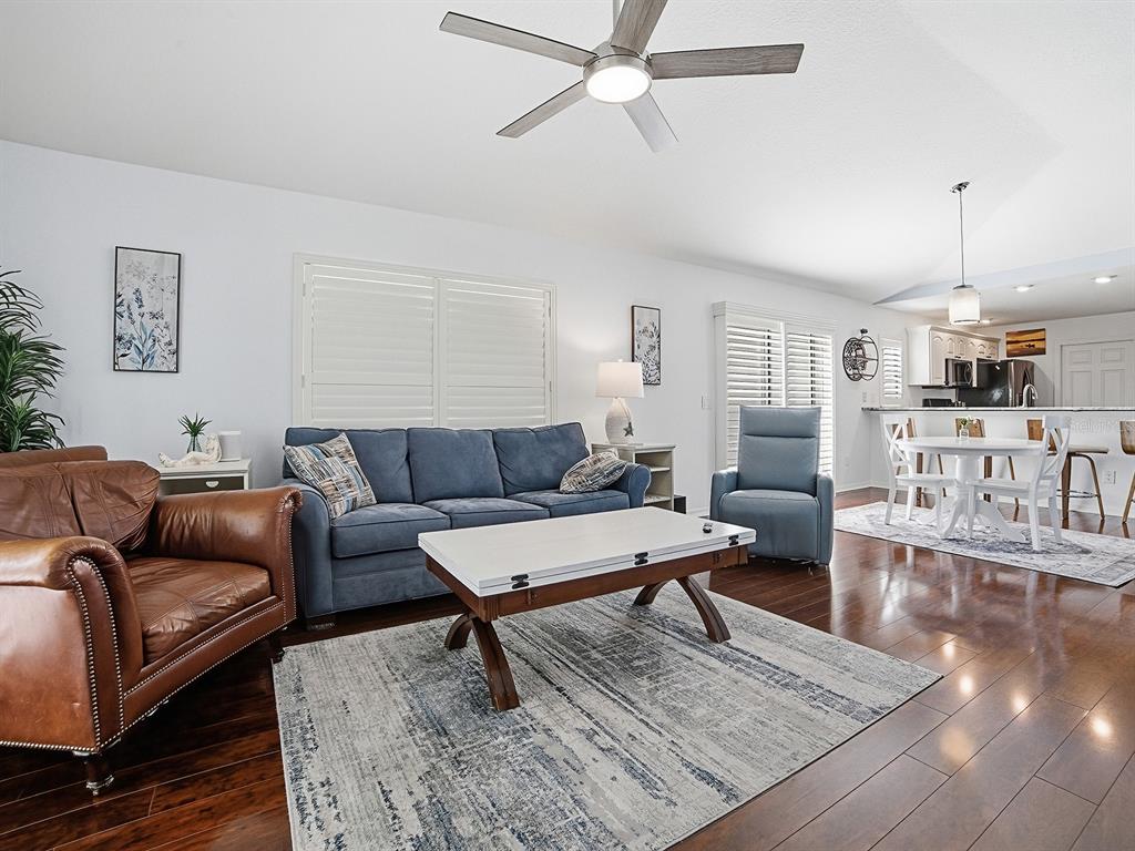 A living room features a blue sofa, brown leather armchair, and a white coffee table — 435 CARLISLE COURT, THE VILLAGES, FL