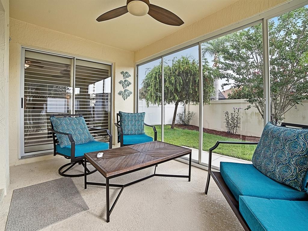 A screened-in patio features a ceiling fan, outdoor furniture, and sliding glass doors — 435 CARLISLE COURT, THE VILLAGES, FL