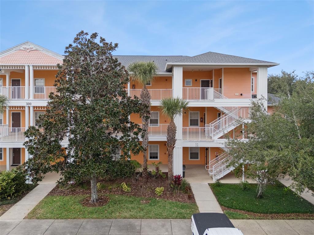 A three-story apartment building with orange siding, white railings, and exterior staircases — 316 NEW PROVIDENCE PROMENADE, DAVENPORT, FL