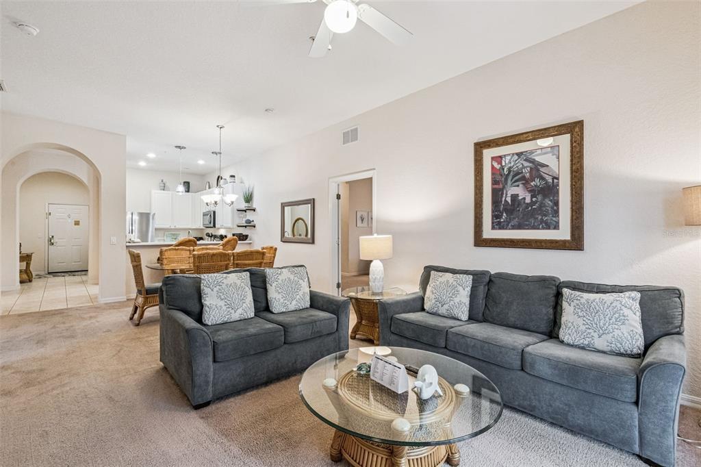 A living room with gray sofas, a glass coffee table, and an adjacent dining area — 316 NEW PROVIDENCE PROMENADE, DAVENPORT, FL