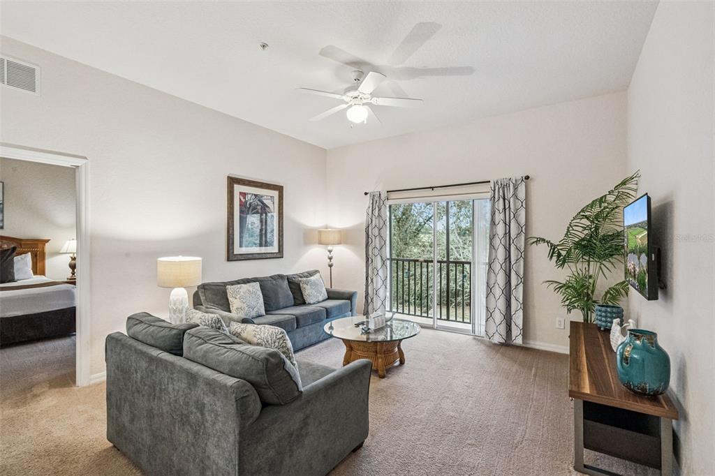 A living room features gray sofas, a glass coffee table, and a sliding glass door — 316 NEW PROVIDENCE PROMENADE, DAVENPORT, FL