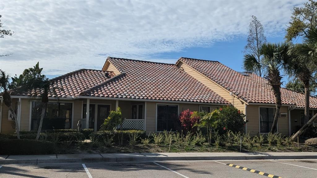 A single-story commercial building with a tiled roof, tan siding, and surrounding landscaping — 11901 N 4TH STREET N UNIT 5212, ST PETERSBURG, FL