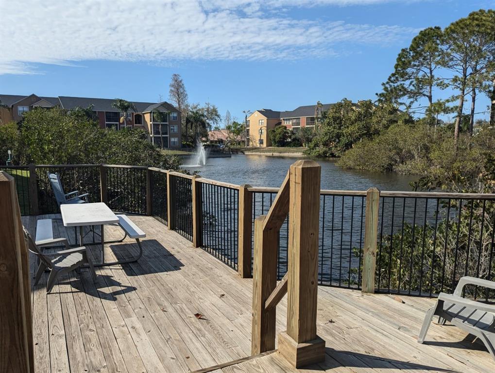 A wooden deck with a picnic table overlooks a pond with a fountain and apartment buildings — 11901 N 4TH STREET N UNIT 5212, ST PETERSBURG, FL