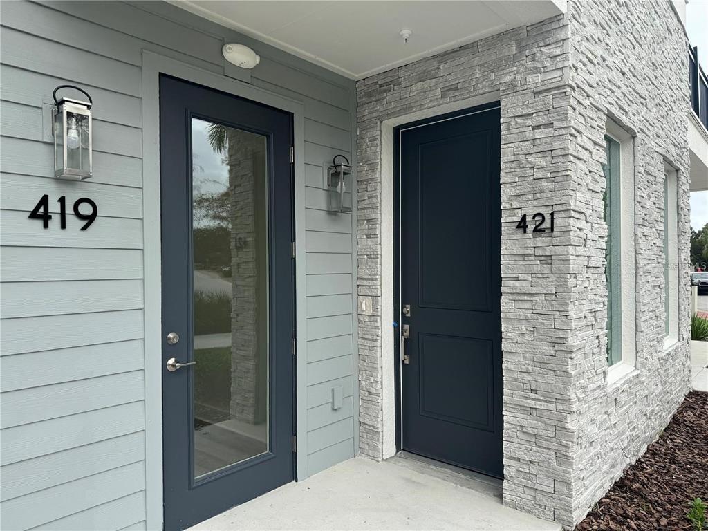 Two dark-colored front doors with house numbers 419 and 421 on a building exterior — 419 MIKE ROBERTO WAY, OVIEDO, FL