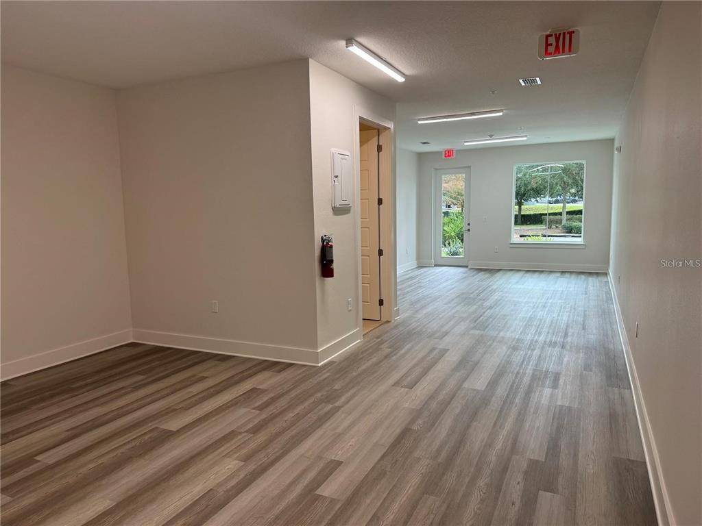 An empty commercial office space features light wood-look flooring, white walls, and a glass door — 419 MIKE ROBERTO WAY, OVIEDO, FL