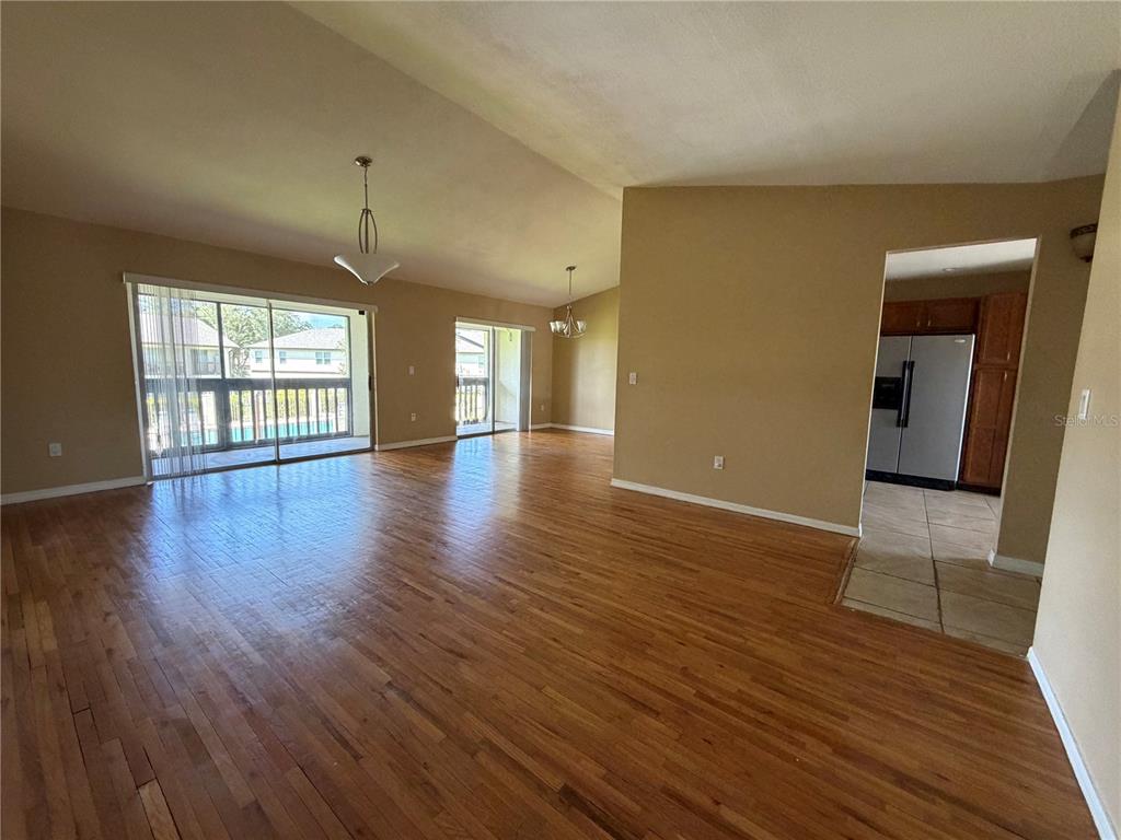 An open-concept living area features hardwood floors, two sliding glass doors, and an adjacent kitchen — 600 NORTHERN WAY UNIT 702, WINTER SPRINGS, FL