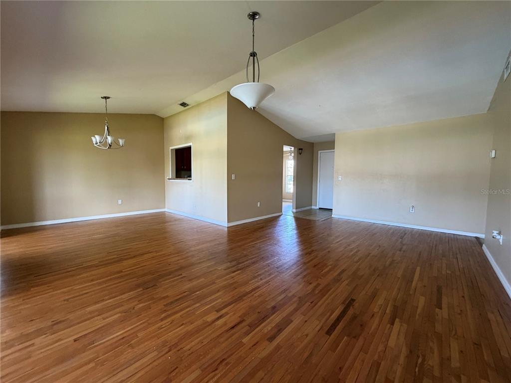 A spacious living area with hardwood floors, vaulted ceilings, and two hanging light fixtures — 600 NORTHERN WAY UNIT 702, WINTER SPRINGS, FL