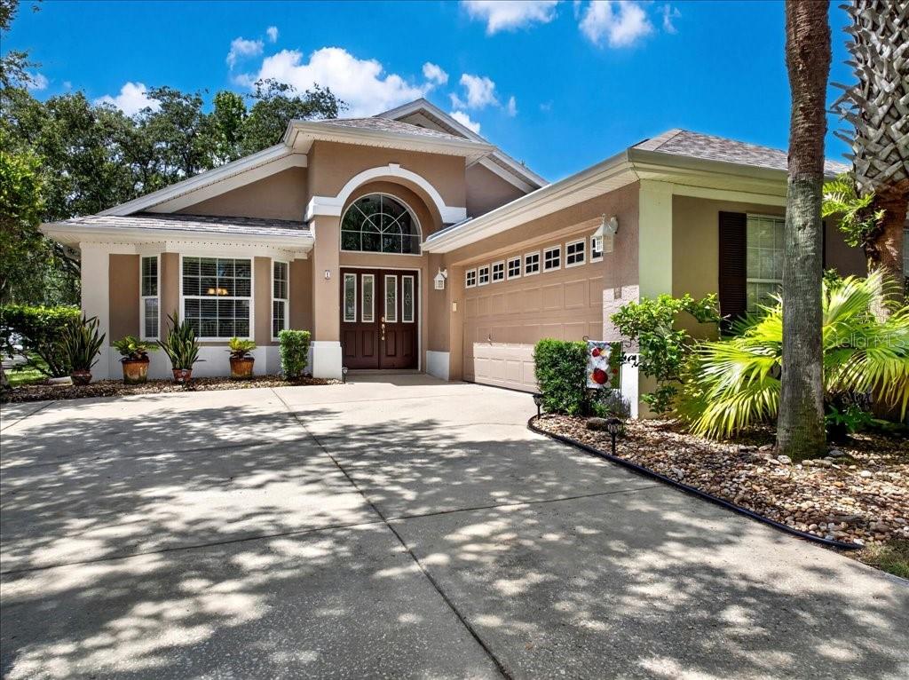 A single-story house with a tan stucco exterior, a two-car garage, and a concrete driveway — 1 GLENEAGLES PLACE, PALM COAST, FL