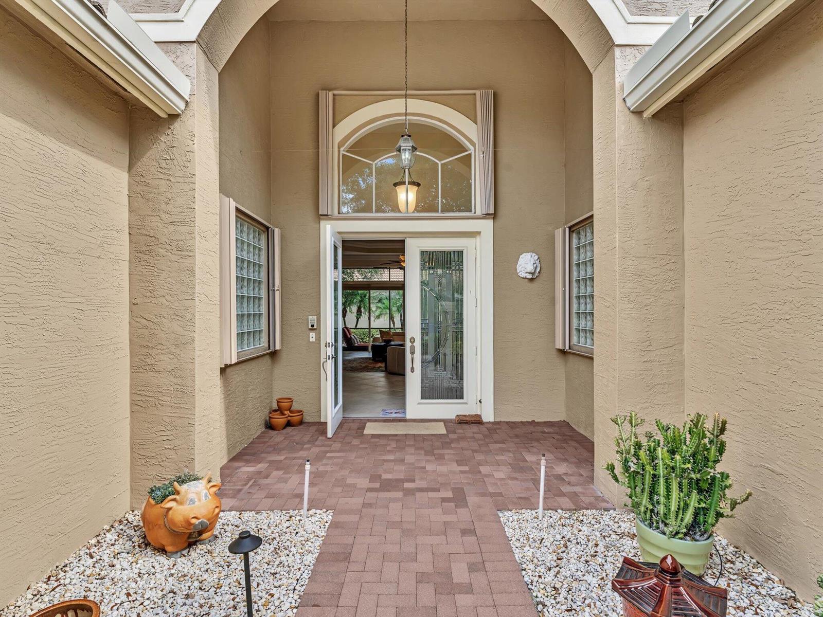 A paved entryway leads to a double-door entrance with a large arched transom window above — 7191 Corning Circle, Boynton Beach FL 33437, BOYNTON BEACH, FL