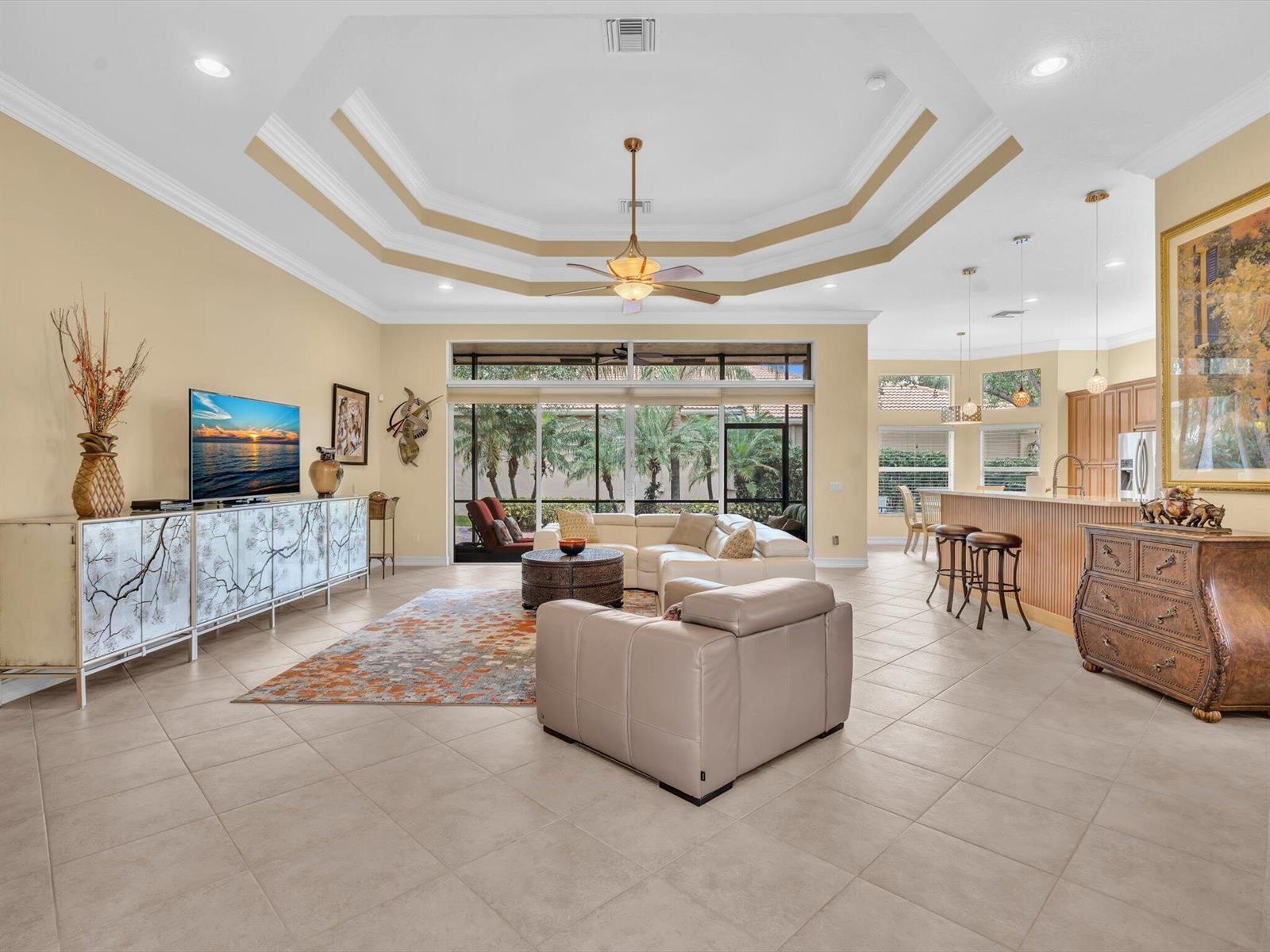 A spacious living room with tile floors, a tray ceiling, and a large sliding glass door — 7191 Corning Circle, Boynton Beach FL 33437, BOYNTON BEACH, FL