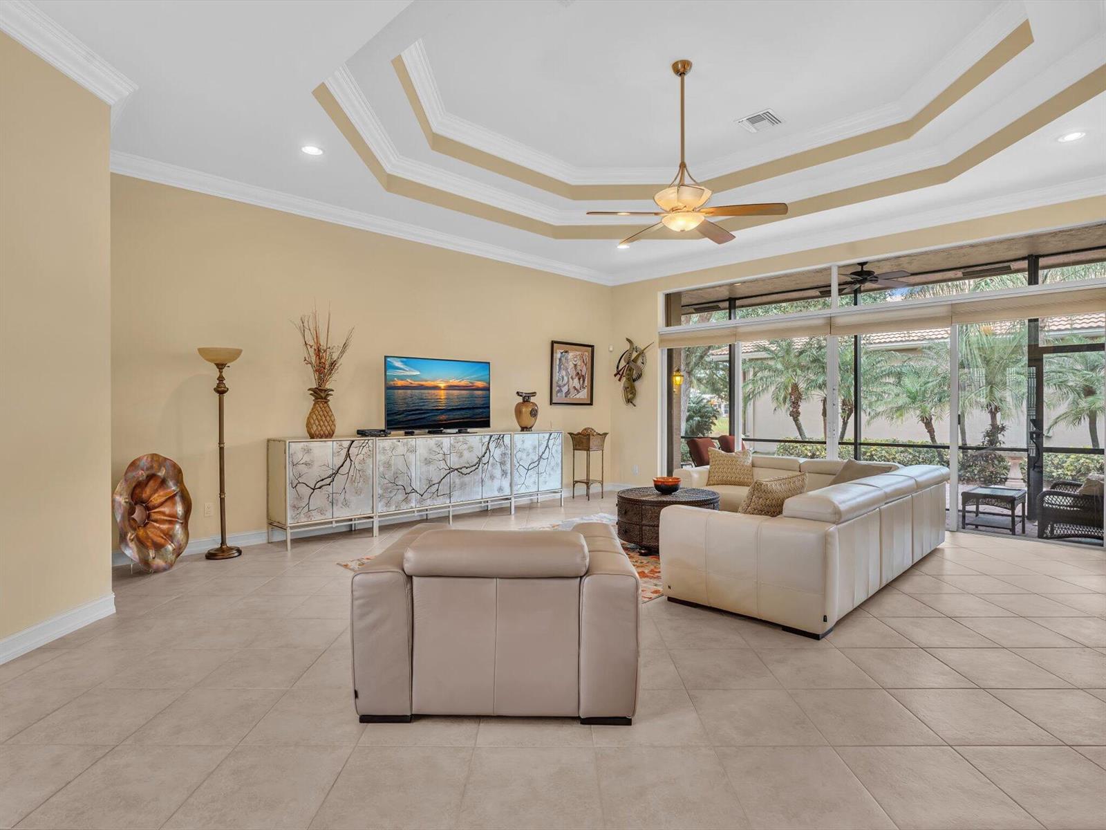 A spacious living room features tile floors, a tray ceiling, and a large sectional sofa — 7191 Corning Circle, Boynton Beach FL 33437, BOYNTON BEACH, FL