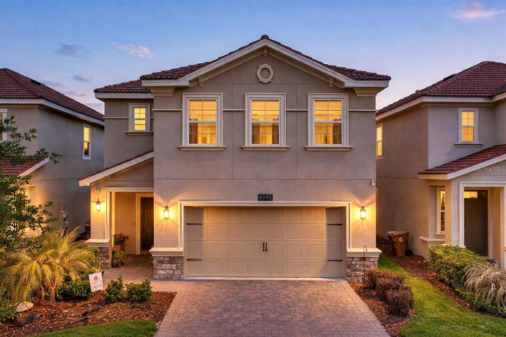 A two-story suburban house with a beige stucco exterior, a two-car garage, and tiled roof — 8995 FLUFFY LIE COURT, DAVENPORT, FL