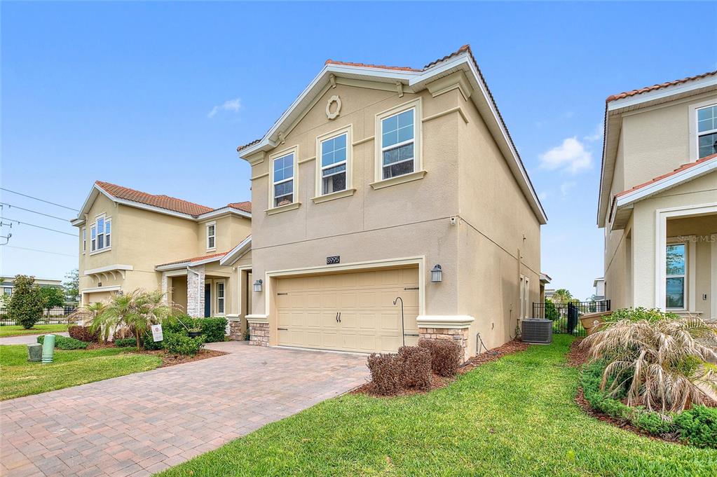 A two-story suburban house with a tan stucco exterior and a paved driveway — 8995 FLUFFY LIE COURT, DAVENPORT, FL