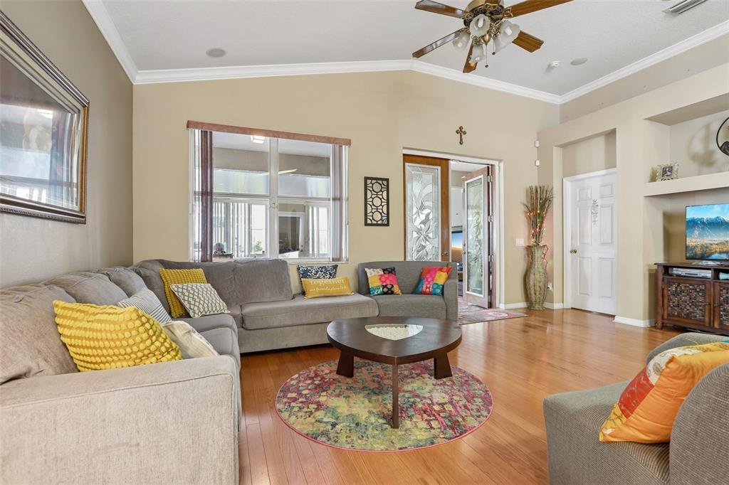 A living room features a sectional sofa, a round coffee table, and hardwood flooring — 4761 WHISPERING WIND AVENUE, TAMPA, FL