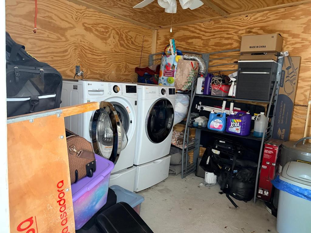A laundry room with a washer and dryer, metal shelving, and plywood walls — 1304 WINDSOR WAY, TAMPA, FL