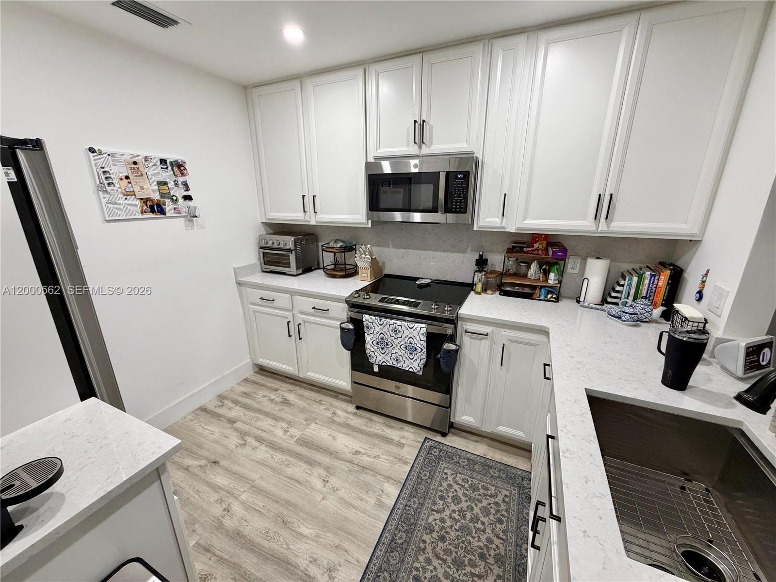 A kitchen features white cabinets, stainless steel appliances, and light-colored countertops — 11259 SW 88th St # 204H, Miami FL 33176, MIAMI, FL
